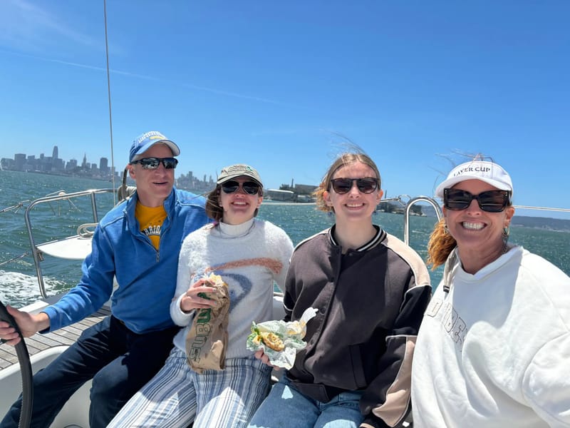 Four friends in the cockpit of a J/105 with the city behind