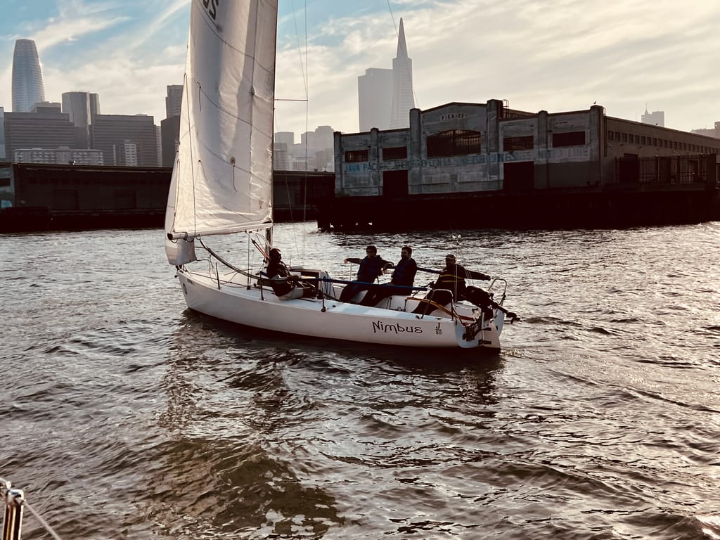 A keelboat sailing past the San Francisco skyline at golden hour
