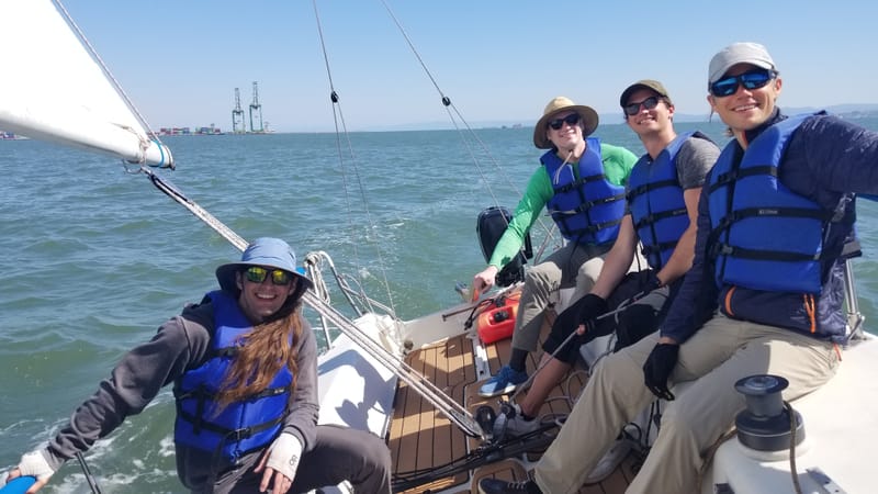 A crew aboard a J/80 on the Bay, smiling for the camera