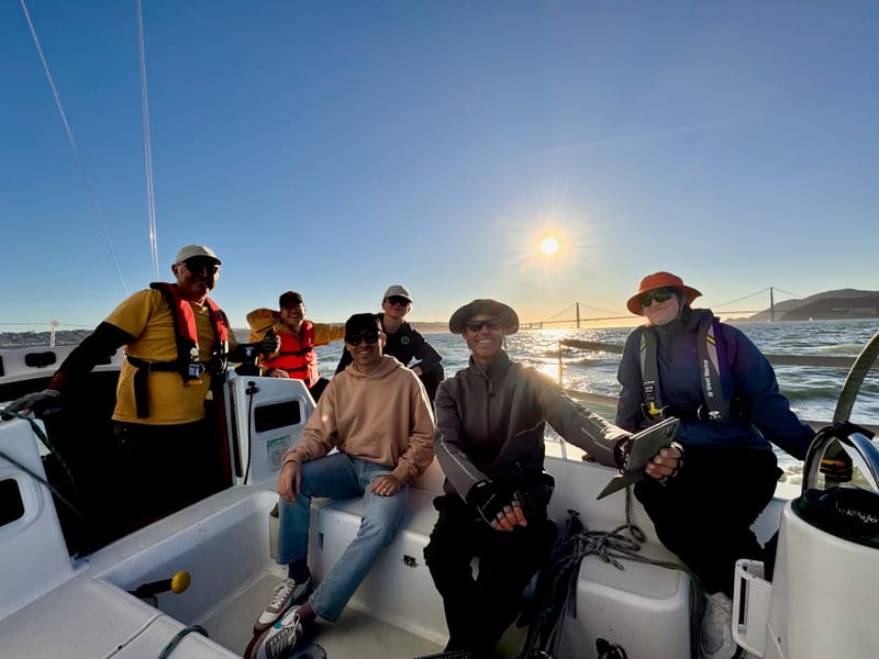 A crew in the cockpit at sunset with the Bay Bridge behind them